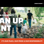group of people walk holding trash bags for clean-up event